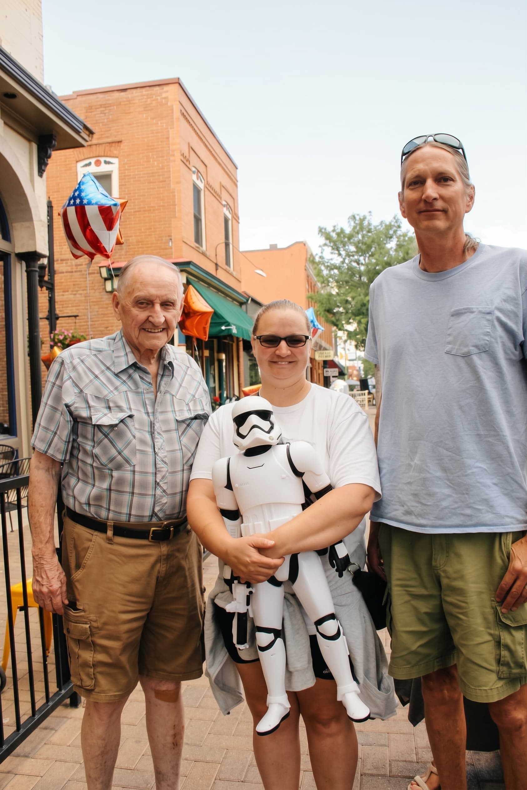 Three generations posing with a Stormtrooper plush outside the shop