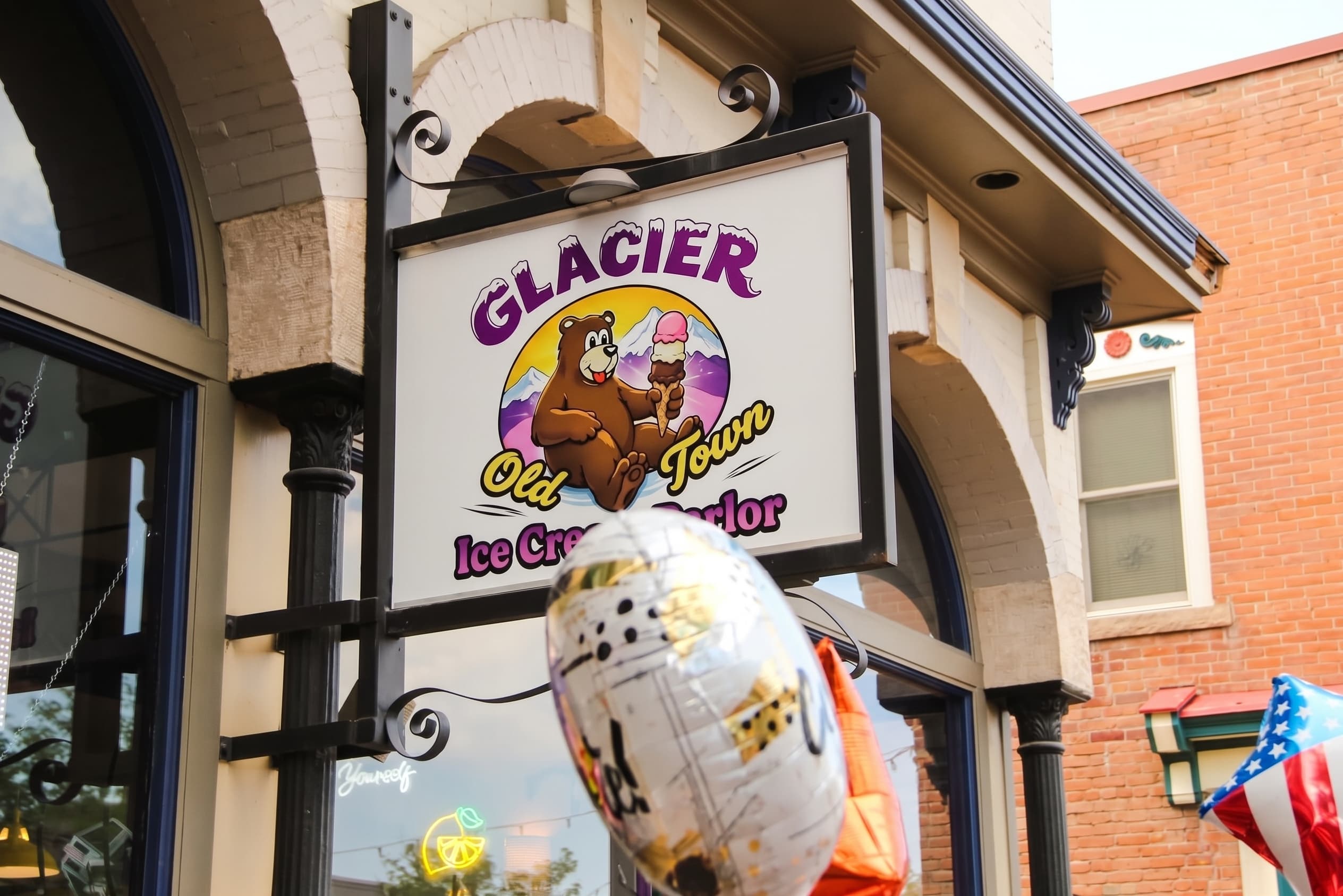 The Glacier Old Town Ice Cream Parlor sign above the entrance with celebration balloons