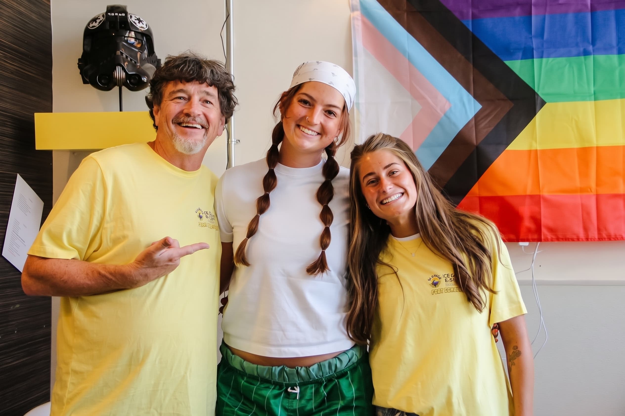 Glacier crew smiling in front of the pride flag inside the shop