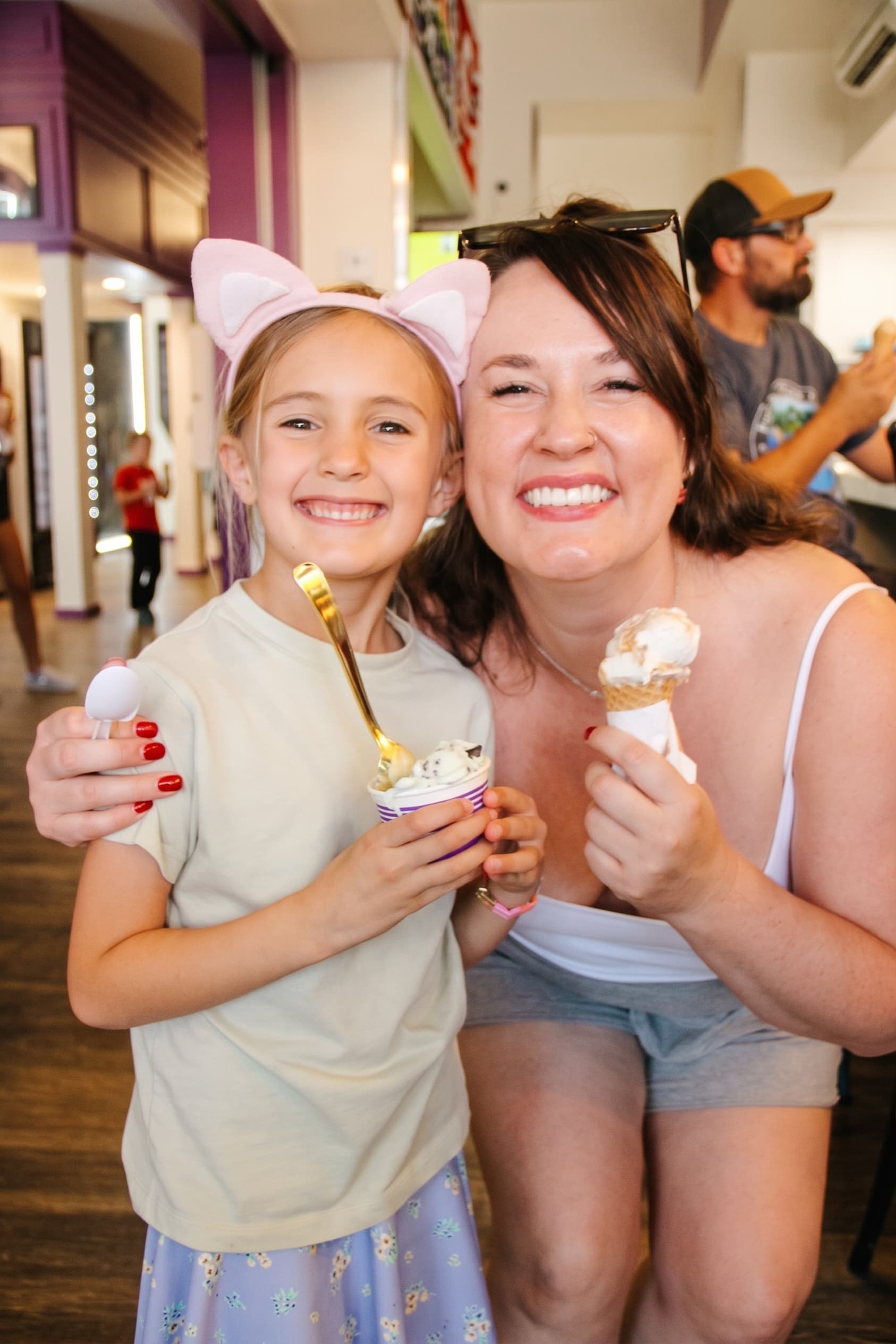 A mom and daughter in cat ears sharing cones