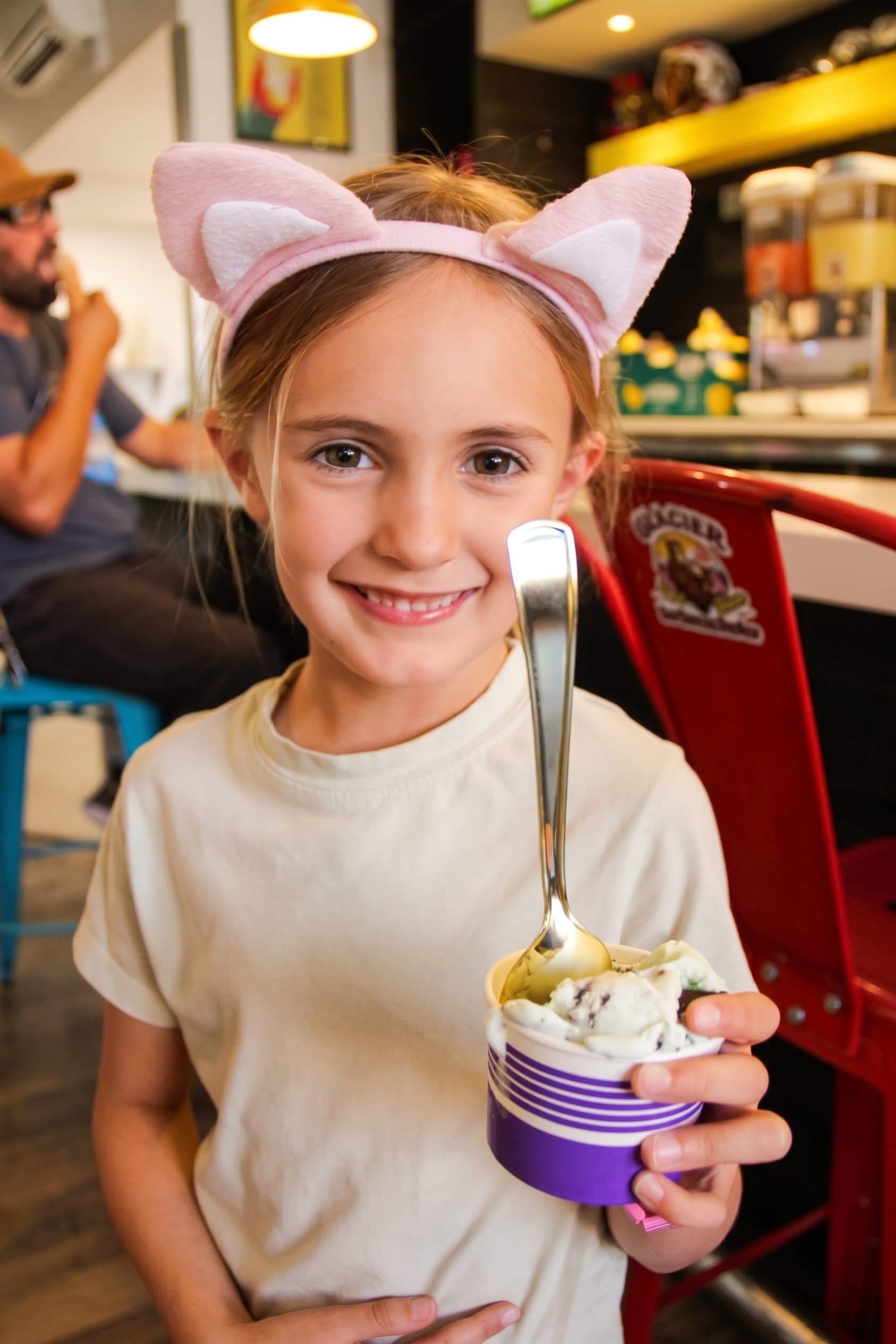 A young guest in cat ears digging into a cup of ice cream