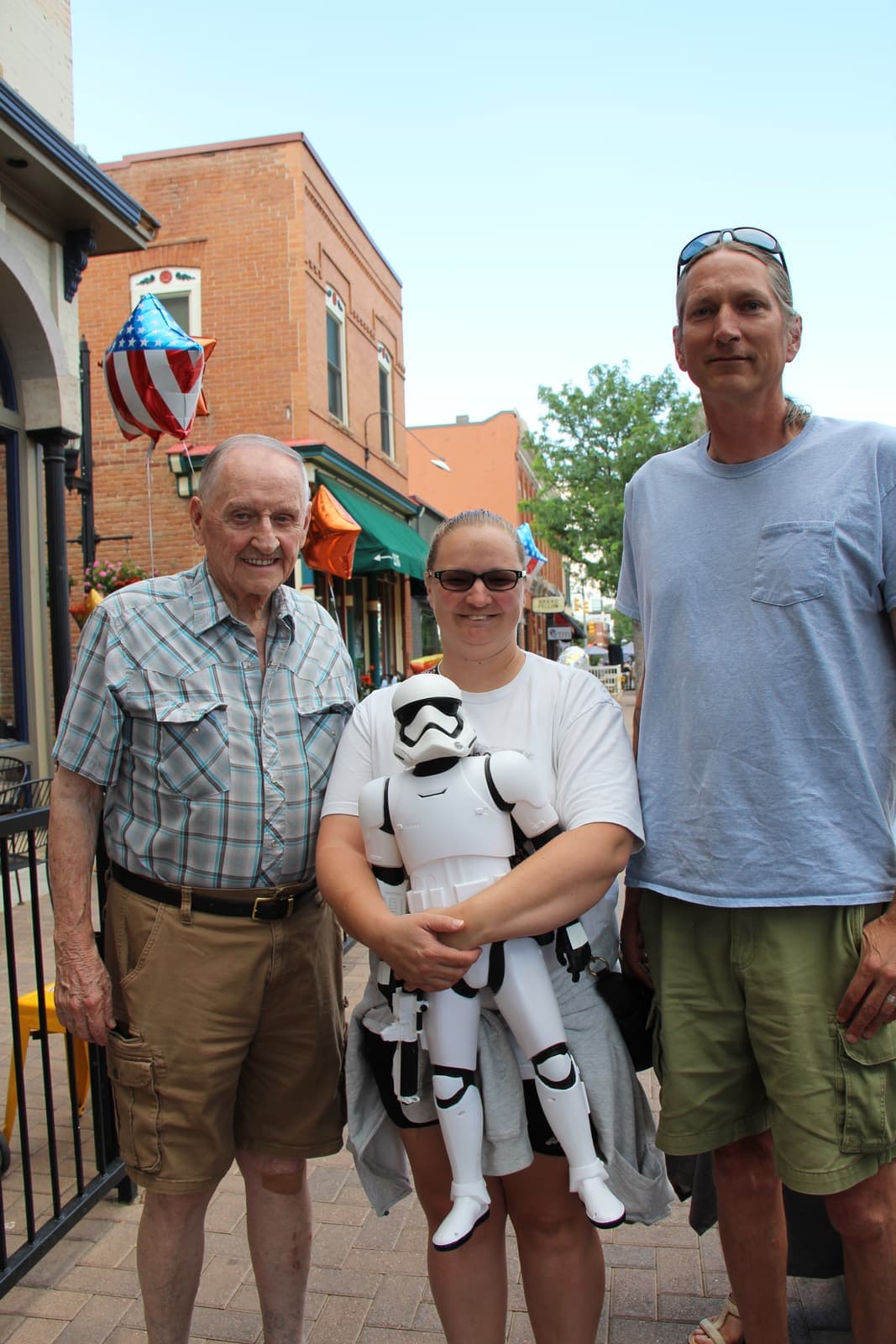 Three generations posing with a Stormtrooper plush outside the shop