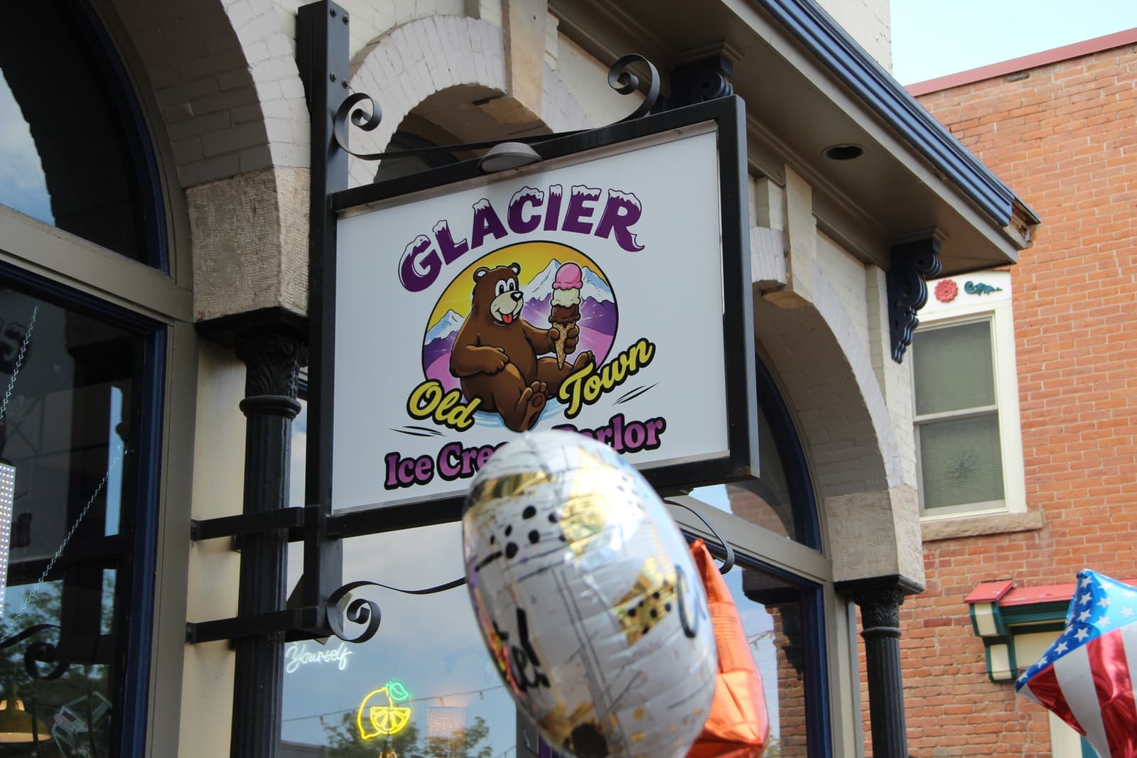 The Glacier Old Town Ice Cream Parlor sign above the entrance with celebration balloons