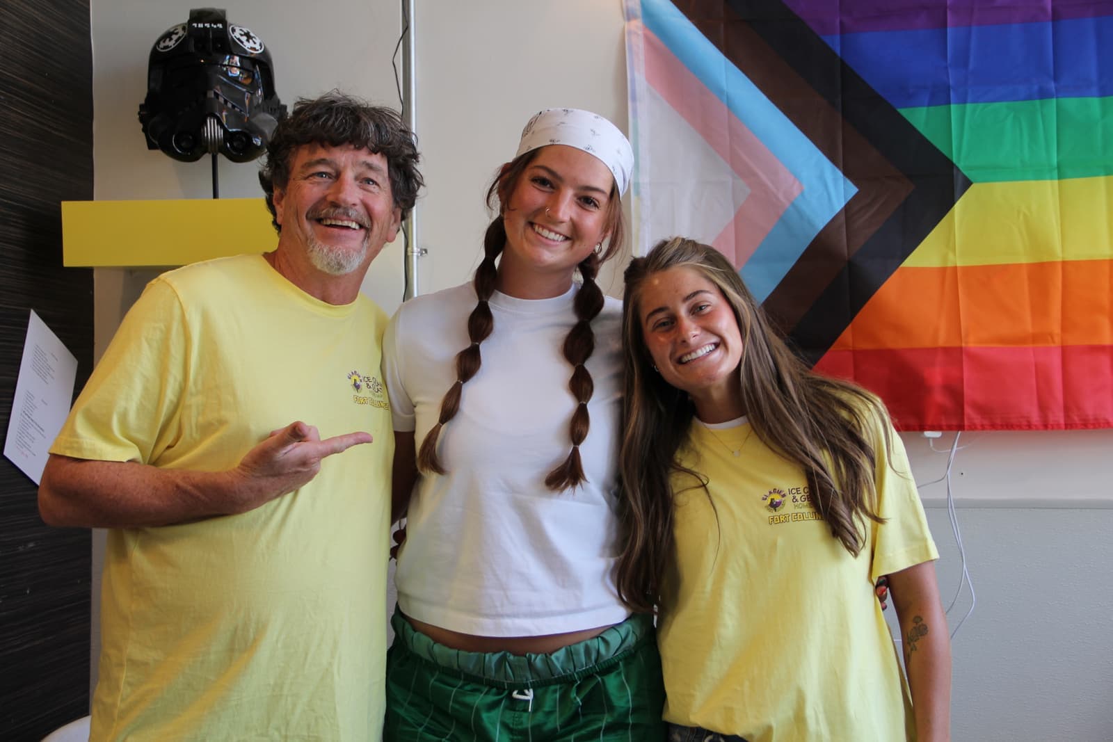 Glacier crew smiling in front of the pride flag inside the shop
