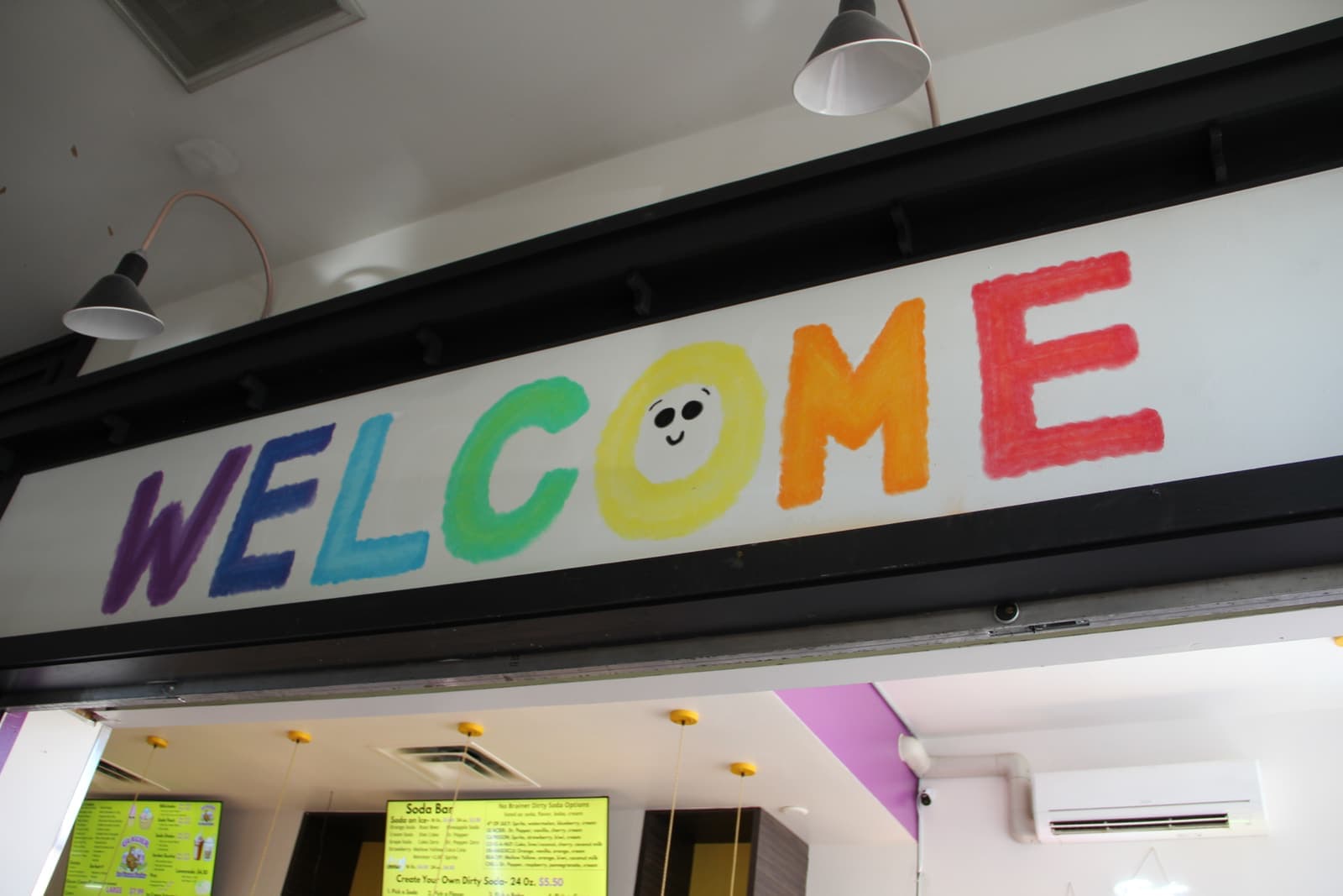The hand-painted rainbow WELCOME letters above the counter