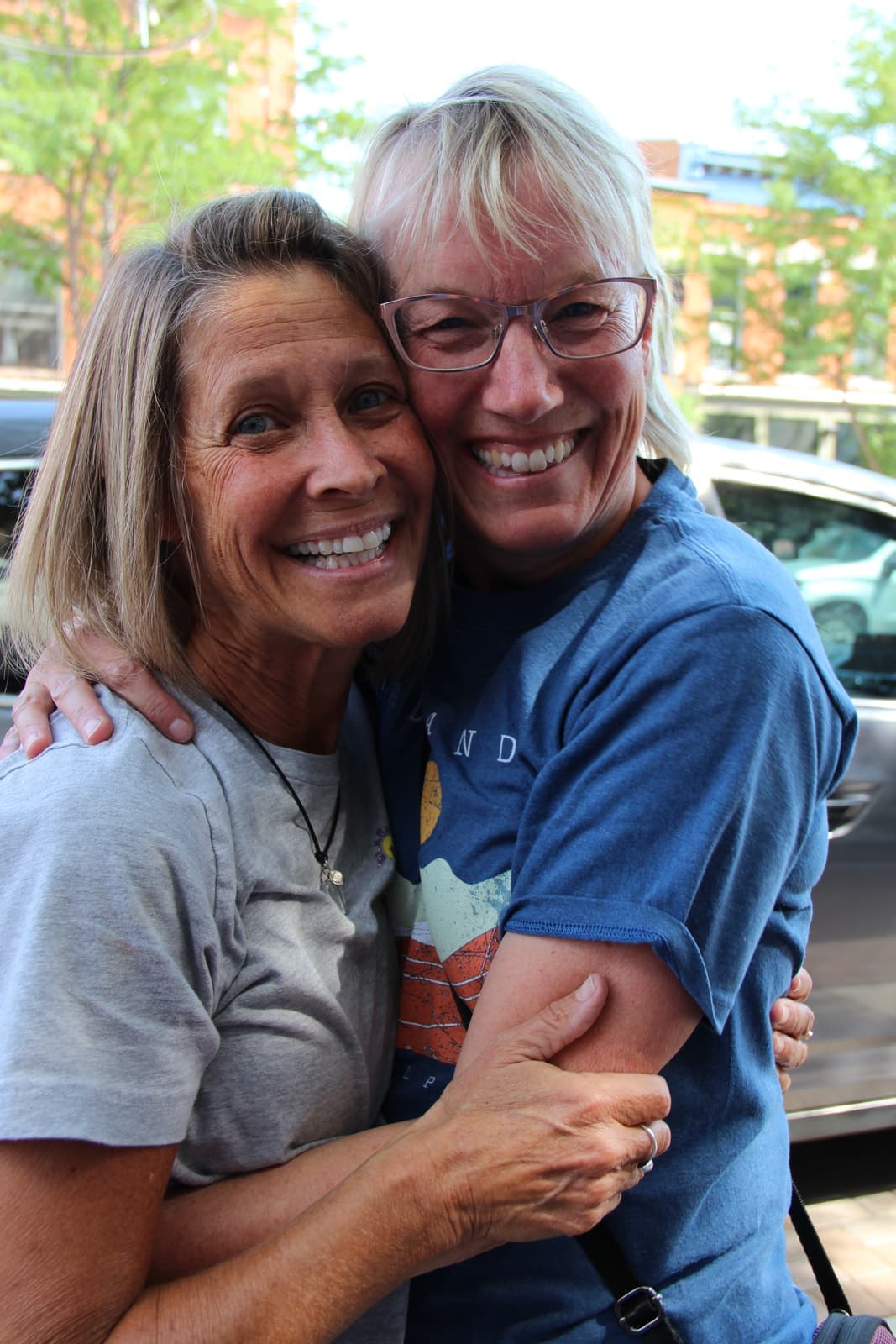 Old friends embracing on the sidewalk outside Glacier