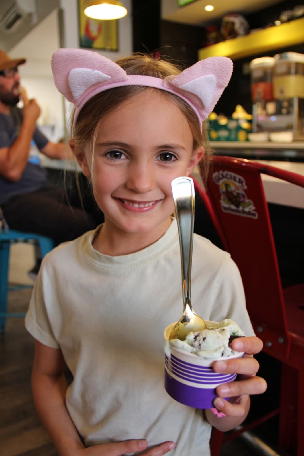 A young guest in cat ears digging into a cup of ice cream
