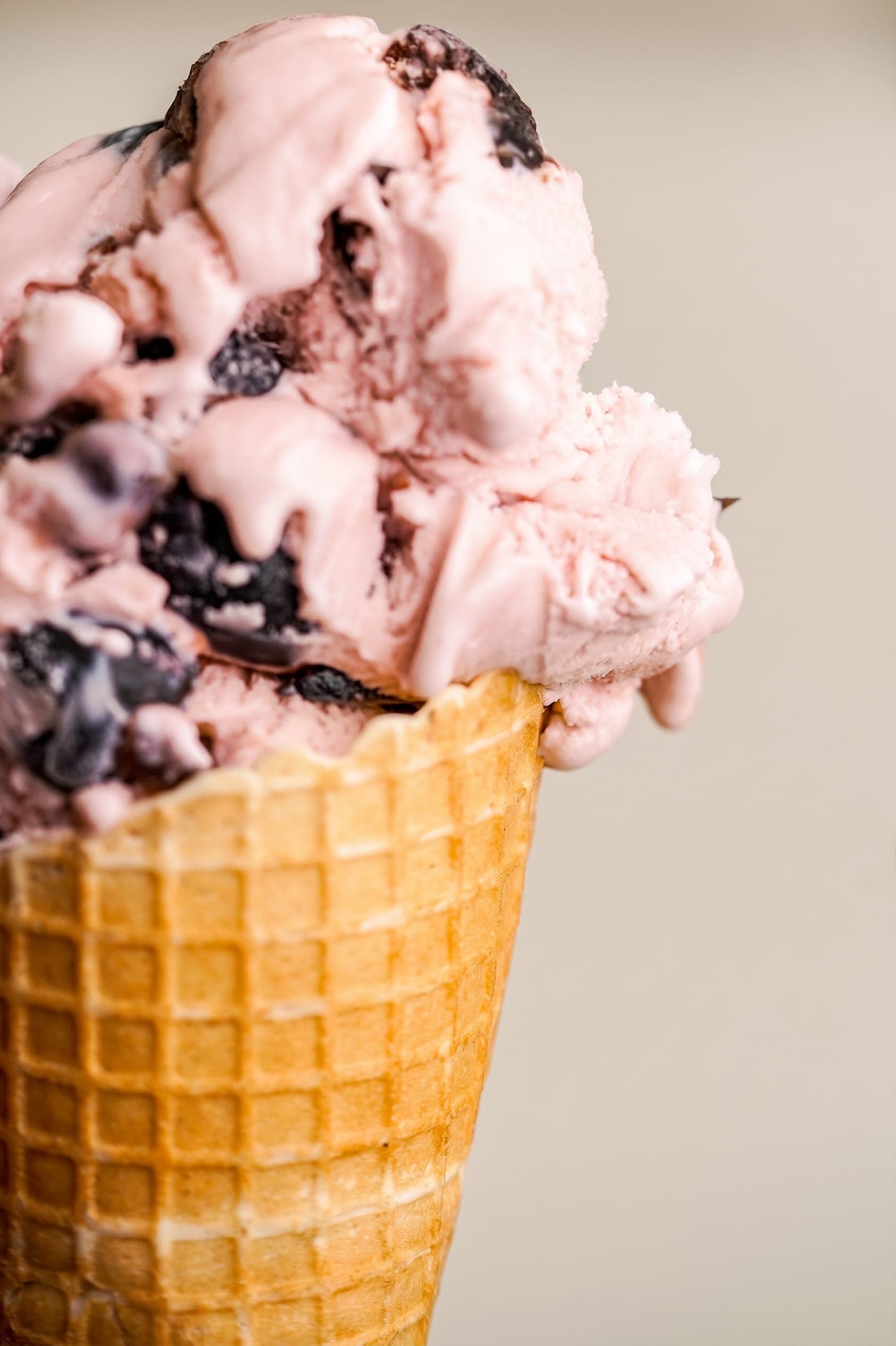 Waffle cone of pink ice cream with dark chocolate chunks