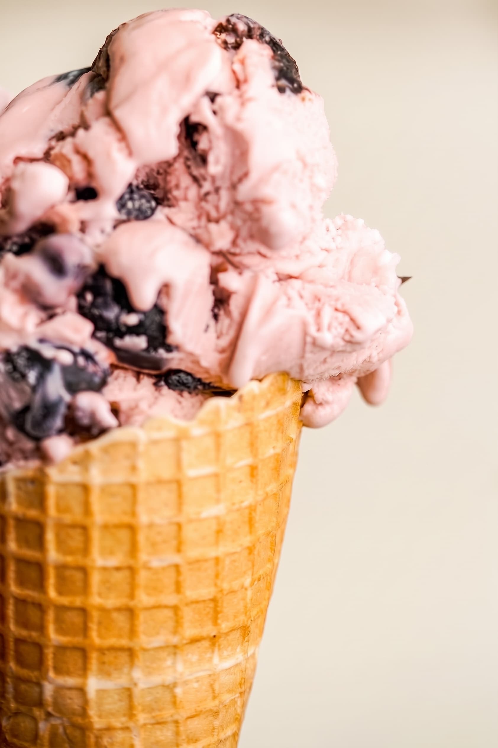 Waffle cone of pink ice cream with dark chocolate chunks
